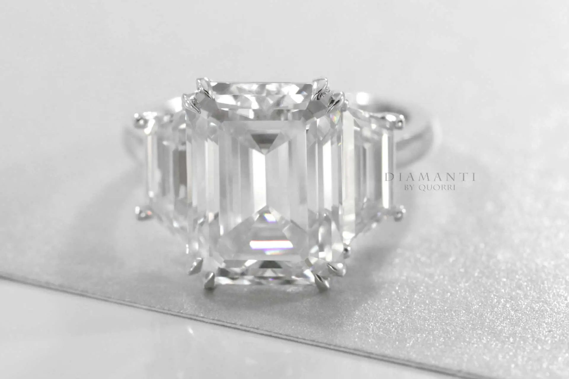 18k white gold dual claw 6 carat emerald and trapezoid three stone lab diamond engagement ring quorri
